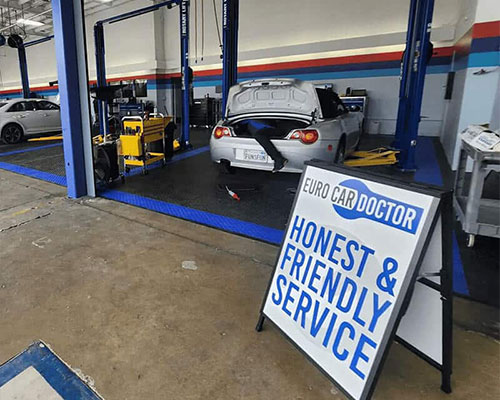 Car at a bay in a repair shop and technician working on the trunk