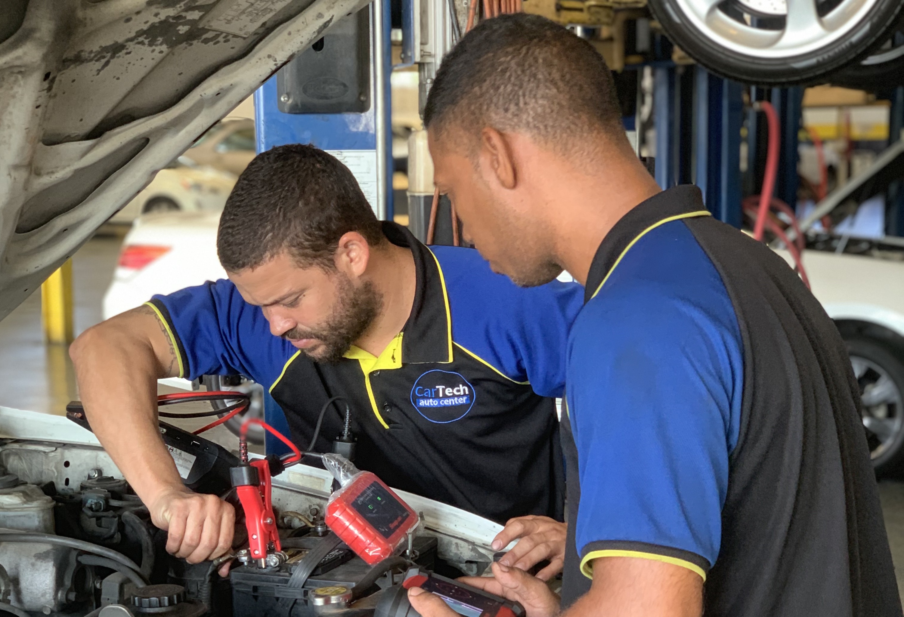 Two technicians working on a car battery